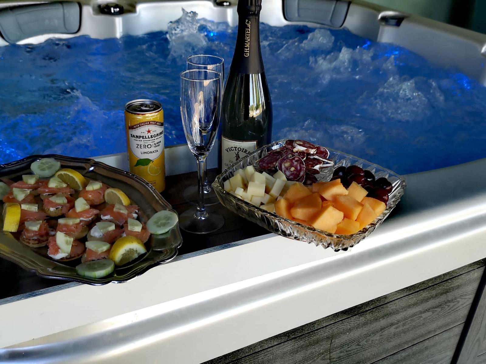 Plateau d'apéritif — blinis au saumon, fromage, fruits — posé au bord du spa