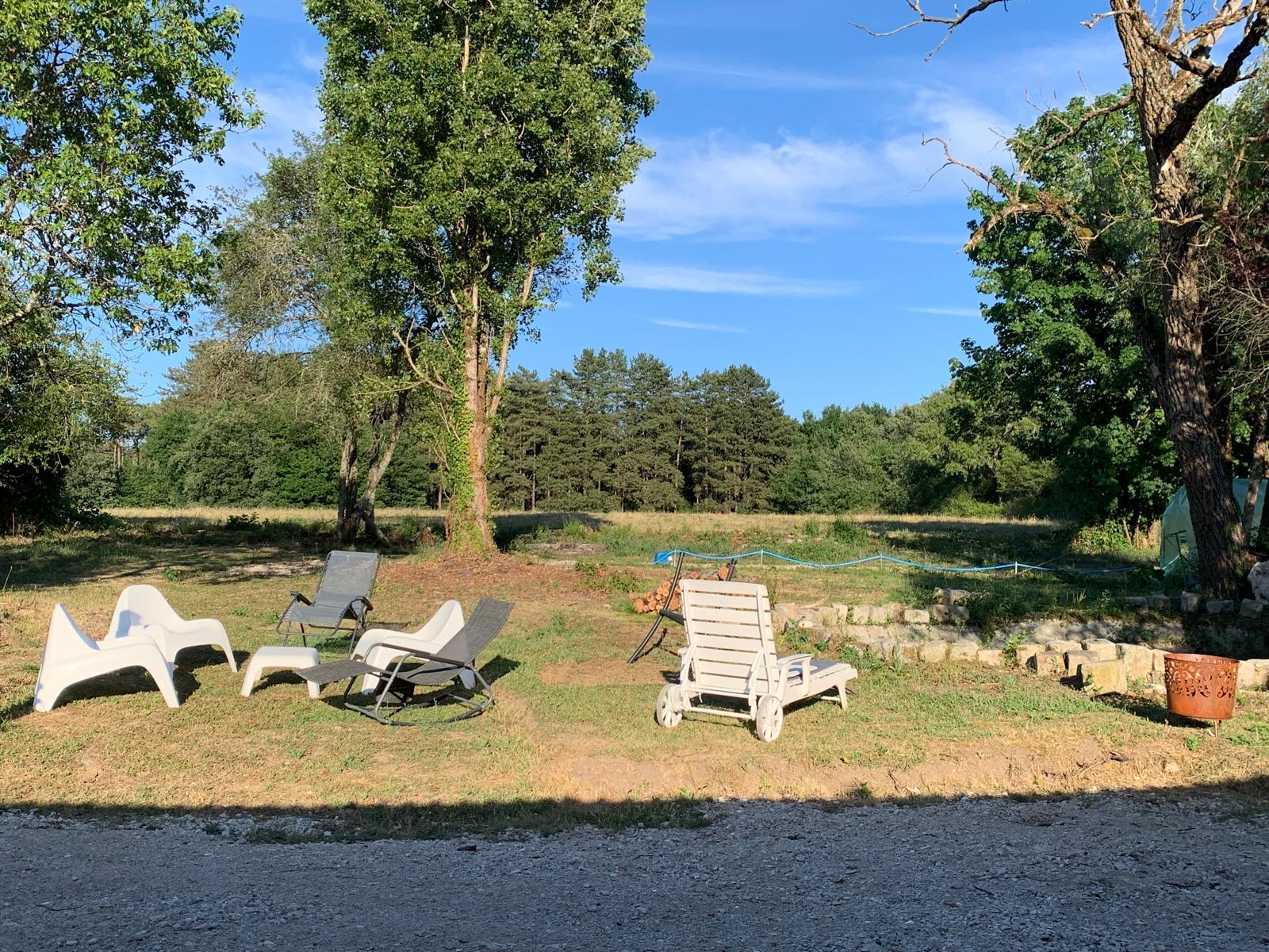 Le jardin de la maison au soleil couchant, transats face à la prairie