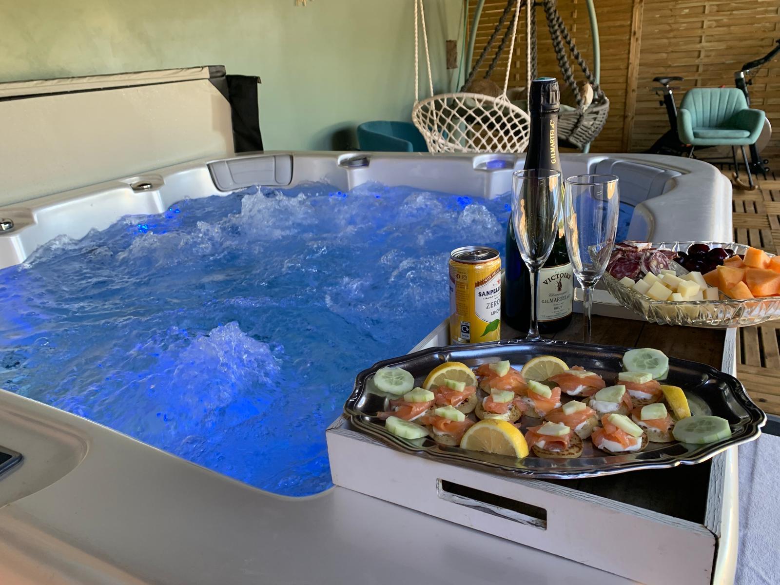 Le spa privatif couvert, en fonctionnement, avec plateau d'apéritif posé sur le rebord