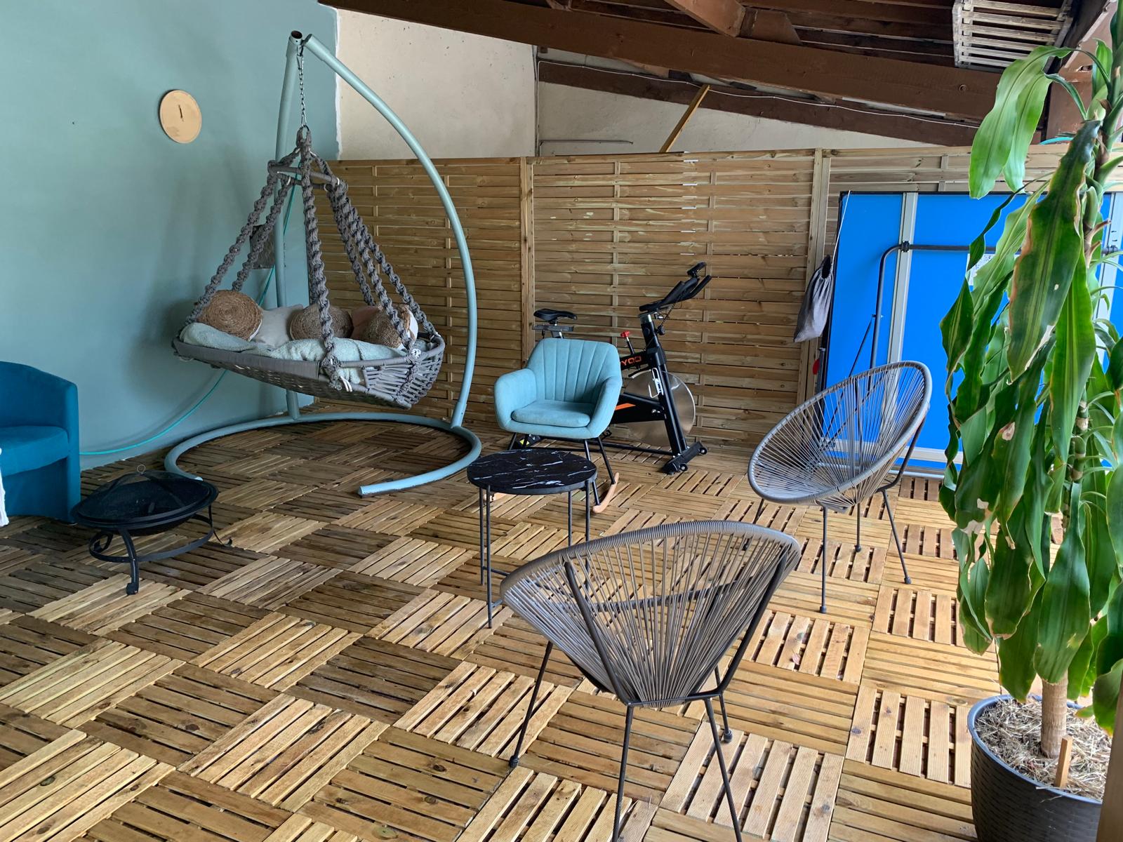La terrasse couverte avec balancelle, fauteuils et table de ping-pong
